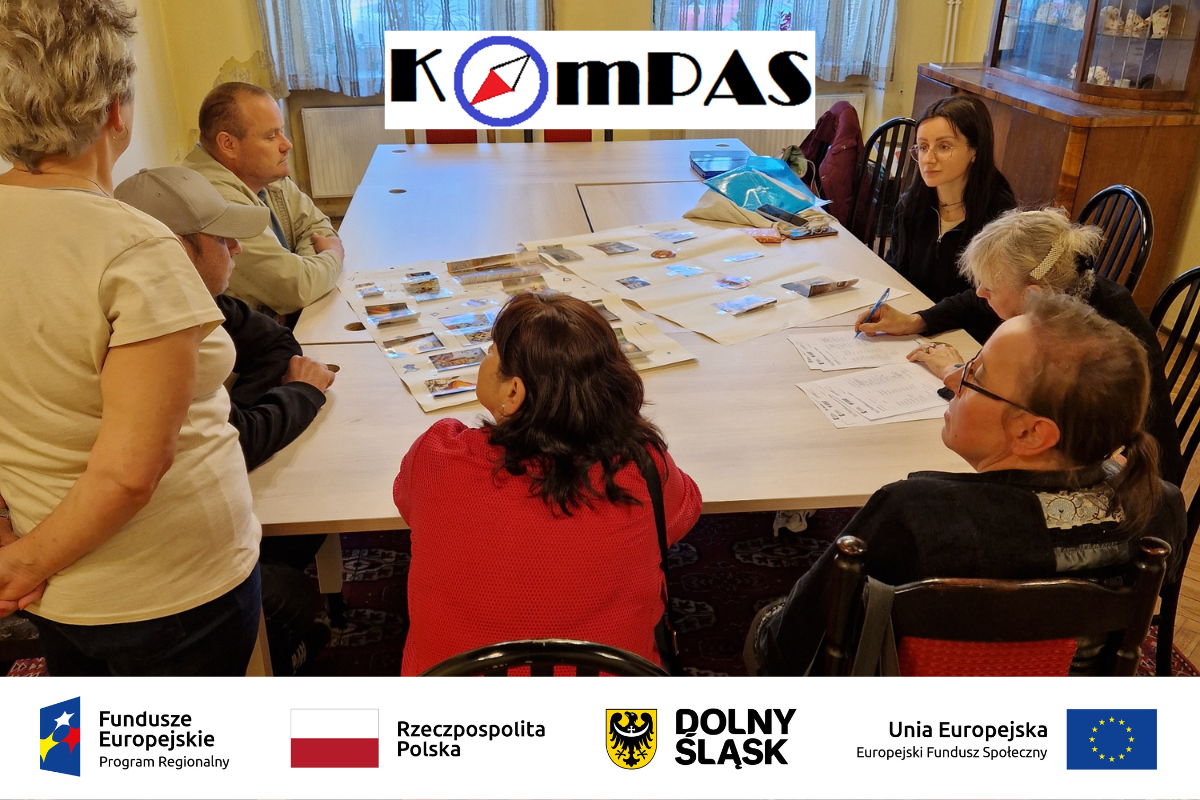 kompas logo projektu, loga projektu KOMPAS flaga Polska / Herb Dolnego Śląska / projekty UE / flaga UE w tle uczestnicy projektu siedzący i rozmawiający przy stole